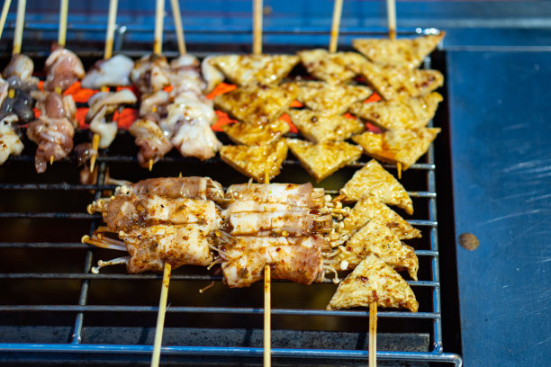 令人垂涎的烤肉串滋滋声在户外烧烤与木炭火焰和芳香香料。这张诱人的图片捕捉到了夏季露天用餐的精髓。图片下载