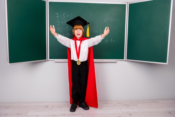 全身照片可爱的小男生勤奋的毕业帽赢得金奖典礼穿着时尚的制服黑板背景图片下载