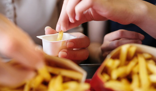 女孩在快餐店吃炸土豆酱图片下载