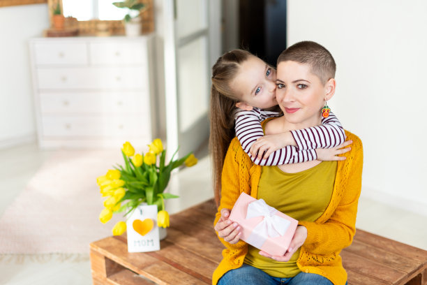 可爱的女儿在家里亲吻拿着礼物的妈妈的照片图片下载