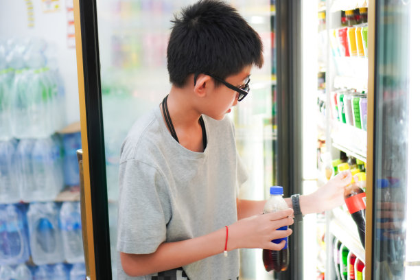 泰国清迈，一个男孩在便利店打开冰箱买软饮料。图片下载