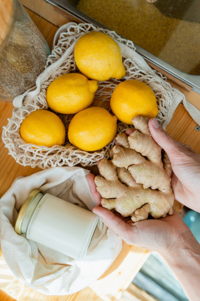 女性双手捧着心形的姜根，旁边是新鲜的柠檬。图片下载