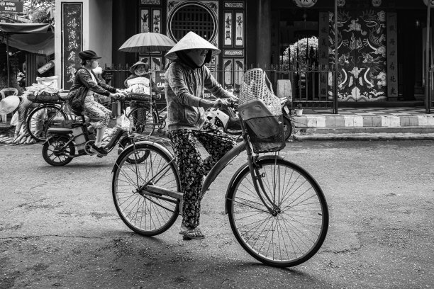 越南会安，一位戴着圆锥形帽子骑自行车的老妇人图片下载