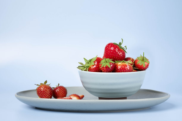 新鲜的草莓在一个碗对蓝色背景股票照片图片下载