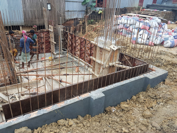 2024年8月5日，孟加拉国达卡。这张照片拍摄了一个熙熙攘攘的建筑工地，两名工人在一片杂乱的木板和金属梁中勤奋地建造一座建筑。图片下载