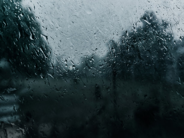 这张照片是在大雨季节从房子里拍摄的，展示了窗户上的露珠，创造了一个美丽的、雾蒙蒙的雨季外面的景色。马来西亚关丹省下大雨图片下载