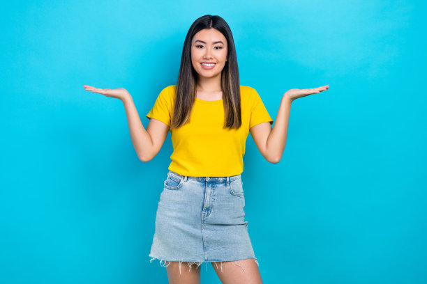 照片中，年轻的黑发亚洲女孩促销员张开手掌，展示两种美容产品孤立的蓝色背景图片下载