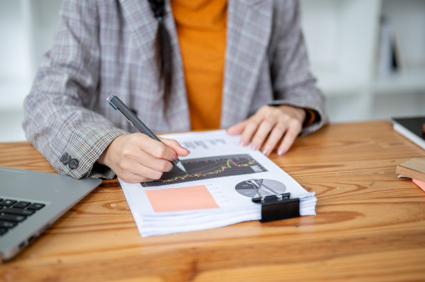 一位女商人在办公室的办公桌前查看商业财务报告的特写图片。图片下载