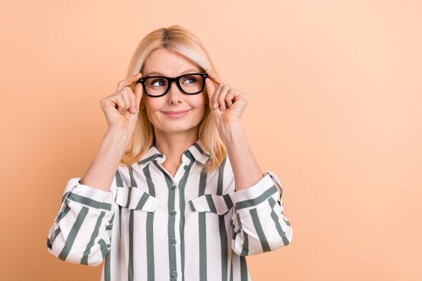 照片上漂亮梦幻的女人穿着条纹衬衫，手臂上戴着眼镜，看起来空空荡荡的米色背景图片下载