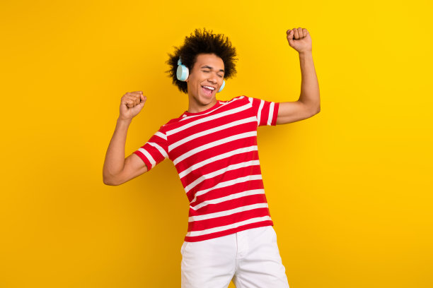 穿着红色t恤耳机的时髦的无忧无虑的男人的照片，有有趣的孤立的黄色背景图片下载