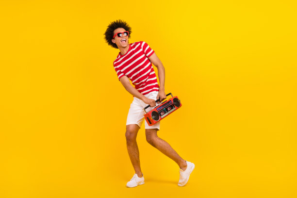 全尺寸照片时髦的家伙跳舞青年聚会携带音响穿衬衫裤子鞋子太阳眼镜孤立的黄色背景图片下载