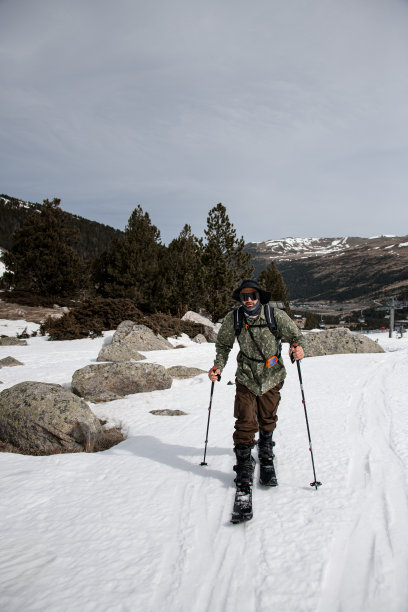 戴着黑色眼镜和宽边帽的滑雪者正在雪地里滑雪图片下载