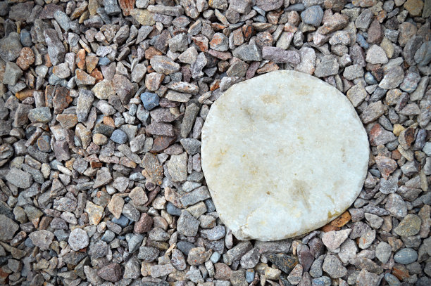 灰色的彩色鹅卵石或砾石水平照片与各种大小不均匀的石头，使粗糙的乡村背景壁纸与一些彩色的小石头和一个圆形的白色大理石圆圈作为标签的复制空间图片下载