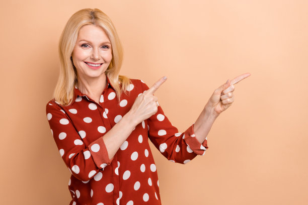 有吸引力的商业女士的照片指导手指看空空间模型广告公司主张孤立的米色背景图片下载