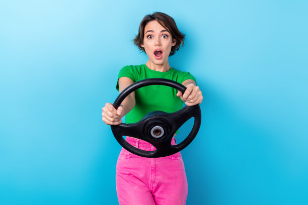 疯狂女孩的照片穿绿色t恤粉红色的裤子拿舵危险坏的道路没有速度限制事故碰撞孤立的蓝色背景图片下载