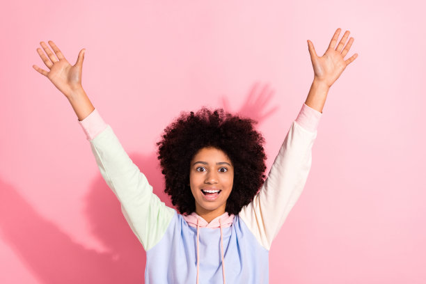 照片相当兴奋的小孩穿着连帽衫微笑上升手臂双手孤立的粉红色背景图片下载