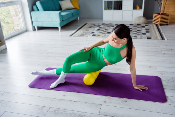 照片性感苗条的年轻女士穿着运动服享受mroll腿按摩在室内家庭工作室图片下载