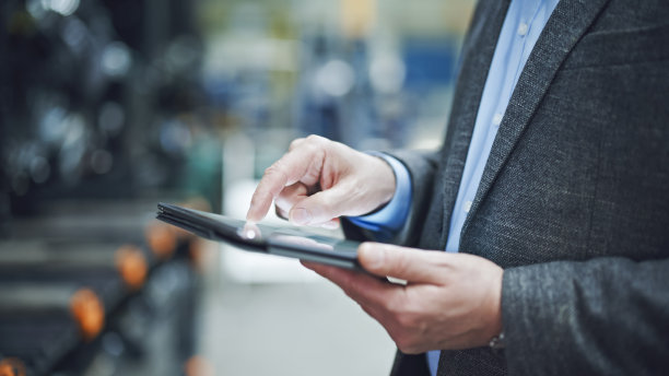 男督察在仓库使用平板电脑。图片展示了技术在管理库存和监督仓库运作中的作用图片下载