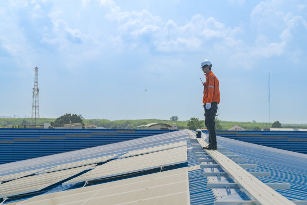 工人技术人员正在屋顶上建造太阳能电池板系统。安装太阳能光伏板系统。男技师走在屋顶结构上检查光伏太阳能组件。图片下载