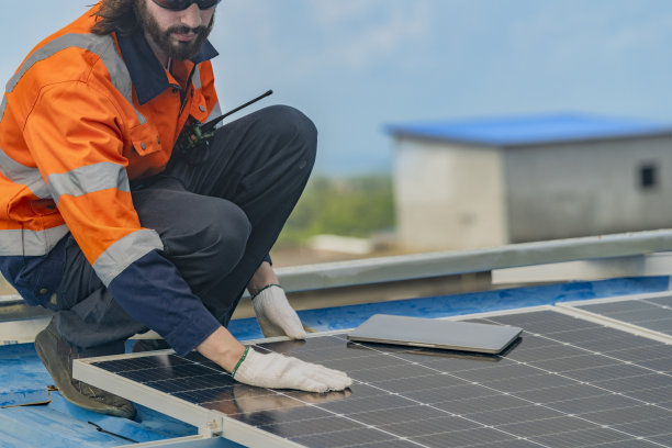 工人技术人员正在屋顶上建造太阳能电池板系统。安装太阳能光伏板系统。男技师走在屋顶结构上检查光伏太阳能组件。图片下载