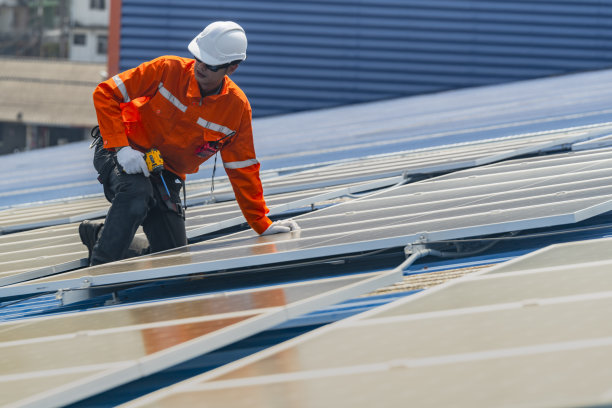 工人技术人员正在屋顶上建造太阳能电池板系统。安装太阳能光伏板系统。男技师走在屋顶结构上检查光伏太阳能组件。图片下载