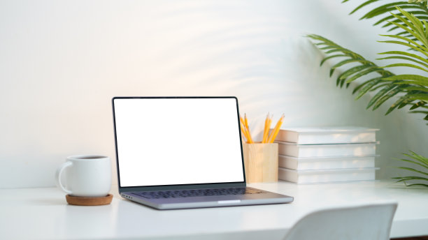 极简主义的家庭办公桌面设置，具有一个光滑的笔记本电脑与一个空白的白色屏幕，理想的添加自己的设计或内容。图片下载