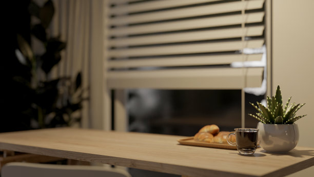 在一个房间里，靠窗的木桌上放着一个咖啡杯和一个盛着羊角面包的盘子。图片下载