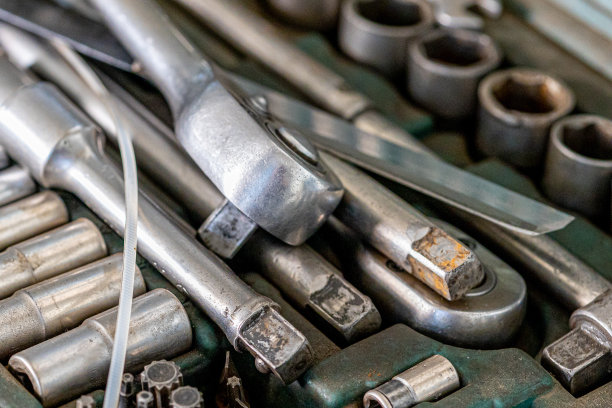 在每个男人的车库里拍摄不同的必要工具和零件的特写照片。汽车检查和汽车服务店的概念。车间的墙上挂着各种各样的工具，尤其是扳手。图片下载