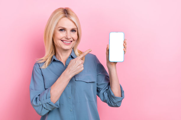 照片的发起人养老金领取者商业妇女穿着正式的衬衫点手指显示手机下载应用程序字典孤立的粉红色背景图片下载