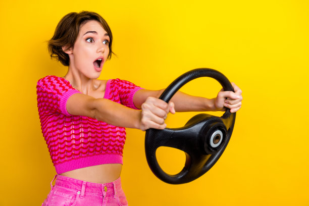 年轻人的照片疯狂的女孩鲍勃棕色的头发粉红色的庄稼顶张开嘴快速度的道路持有方向盘汽车孤立的黄色背景图片下载