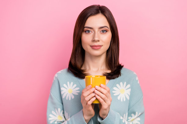 照片的好心情积极的女人穿着蓝绿色的衣服享受饮料香气孤立的粉红色背景图片下载