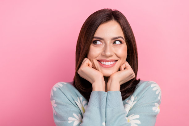照片的梦幻光泽的女人穿着蓝绿色的衣服手臂脸颊看起来空白空间孤立的粉红色背景图片下载