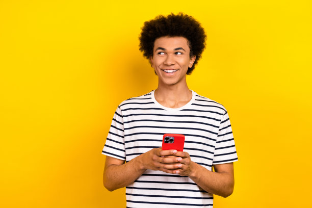 照片的青年积极的家伙穿条纹t恤拿着智能手机看空空间搜索网页孤立的黄色背景图片下载