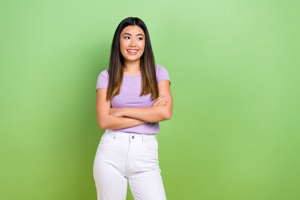 照片中，迷人的日本韩国年轻女子双臂交叉，看起来空无一人，穿着时髦的紫色衣服，孤立在绿色的背景下图片下载