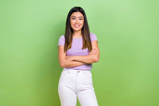 照片中，自信的中国商务女士穿着紫色t恤，双手交叉，对项目经理感到满意，绿色背景被孤立起来图片下载
