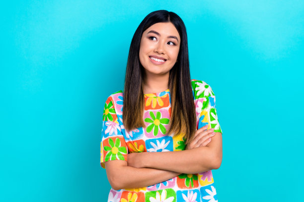 照片中开朗梦幻的女士穿着印花t恤，双臂折叠，看起来空落落的蓝色背景图片下载