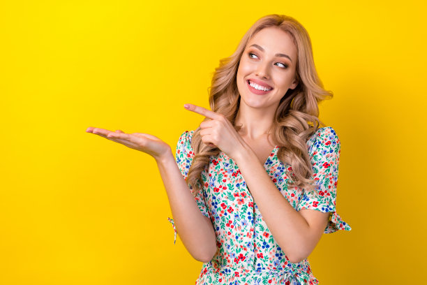 照片中可爱的梦幻女子穿着印花沙拉芬指着手指抱着手臂空白的空间孤立的黄色背景图片下载