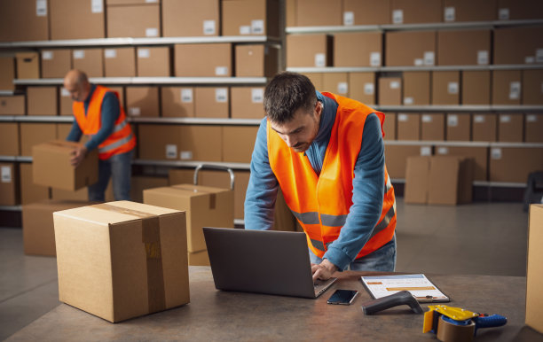 年轻的仓库员工用笔记本电脑工作图片下载