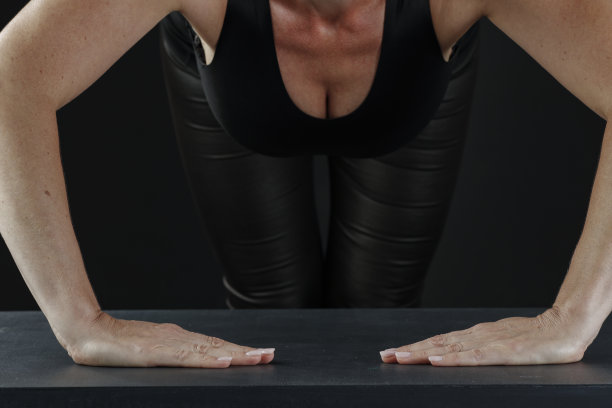 健身房训练。广告产品和他们的蒙太奇在照片的地方。一名女子在健身房用杠铃和哑铃锻炼。照片中只能看到身体的一部分。黑色背景。图片下载