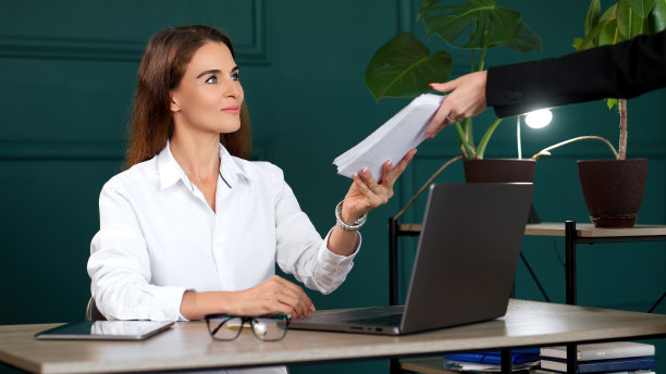 在她现代化的办公室里工作的女商人，审阅交给她的文件或发票。适合专业工作、办公效率、财务管理等主题。图片下载