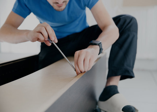 一个年轻人正在修理一个旧衣柜。图片下载