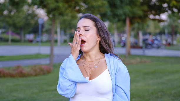 一个年轻漂亮的女商人在公园里打哈欠图片下载