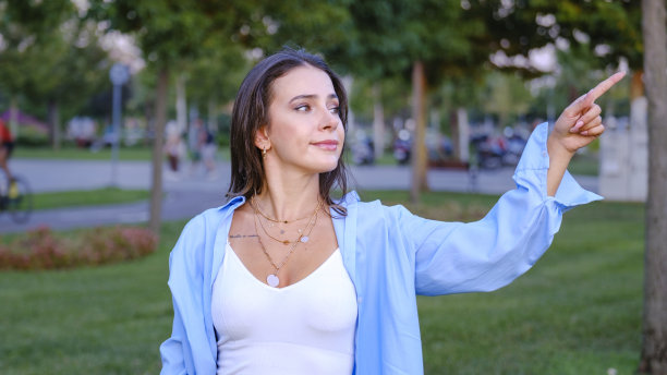 在公园里，一位年轻漂亮的女商人用食指指着屏幕的一角图片下载