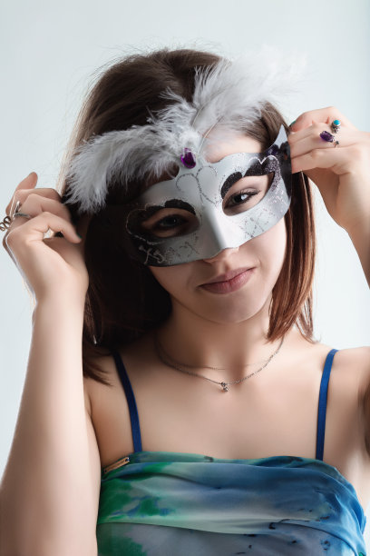 年轻女子用羽毛调整威尼斯狂欢节面具图片下载