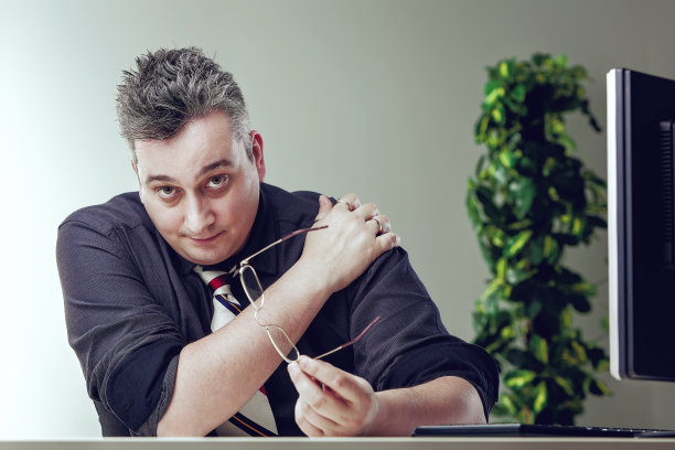 胖乎乎的会计在办公桌前按摩酸痛的肩膀图片下载