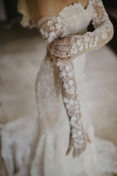新娘戴着长长的蕾丝手套，在一个特写镜头中被捕捉到，她的优雅体现在精致的细节上。库存图片图片下载