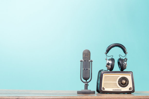 复古的麦克风，旧收音机和耳机上的木桌前薄荷蓝色的背景。复古滤镜照片图片下载