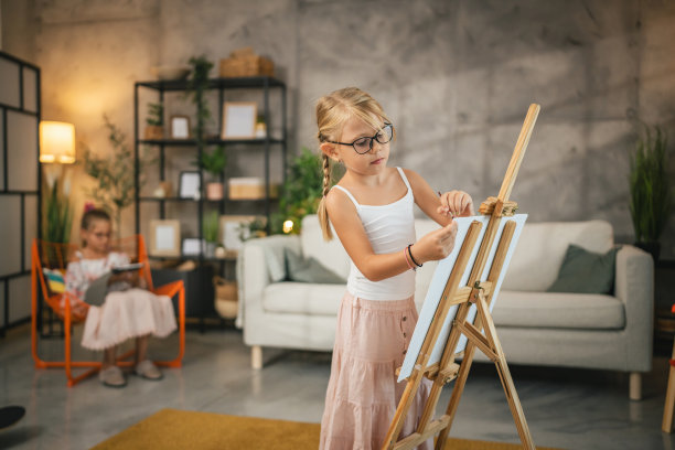 小女孩在家里用毛笔和水彩在帆布架上作画图片下载