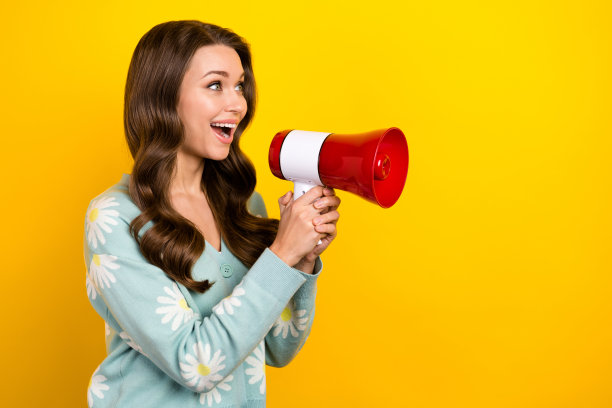 年轻美女的照片拿着扬声器，声音尖叫，看着空荡荡的空间，购物建议，提供孤立的黄色背景图片下载