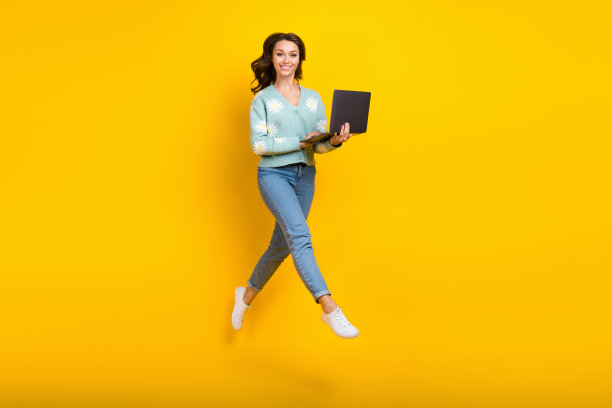 年轻女士的全身照片，积极的远程工作者会议在线跳跃，同时运行地铁与笔记本电脑隔离在黄色背景图片下载